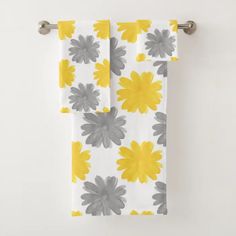 two yellow and gray flowers are hanging on a towel rack in front of a white wall