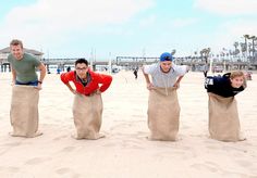 three men standing in the sand with their hands on their hipss