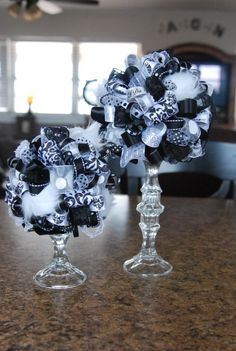 two clear vases with black and white flowers on them sitting on a counter top