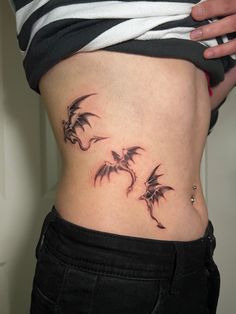 a woman's stomach with three small dragon tattoos on her belly and the lower part of her abdomen