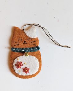 an ornament with a cat on it is hanging from a string and has beads around its neck