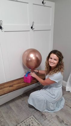 a woman is sitting on the floor with a balloon in her hand and smiling at the camera