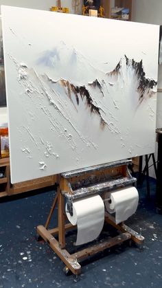 a painting is being worked on in an art studio with mountains painted on the canvas