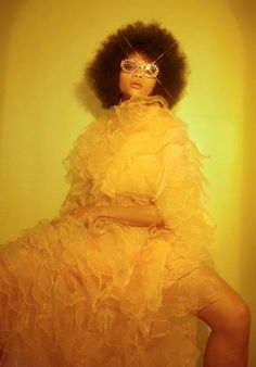 a woman in a yellow dress with an afro hairstyle and glasses on her face