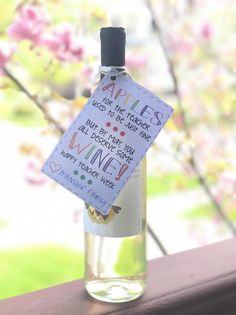 a wine bottle with a note attached to it sitting on a window sill in front of a flowering tree