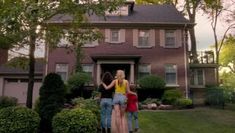 three people standing in front of a house