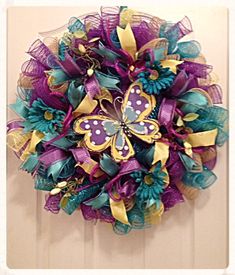 a purple and teal wreath with butterflies on the front door for someone's house