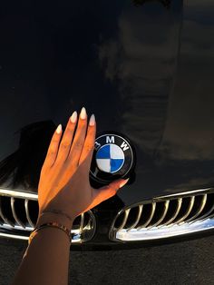 a woman's hand on the hood of a black car with a bmw emblem