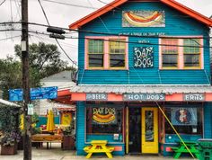 a blue building with two yellow benches in front of it and other colorful buildings behind it