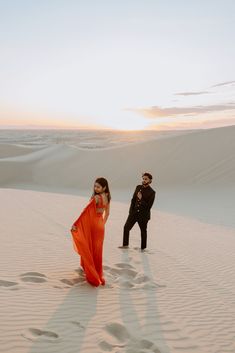 a man and woman standing in the sand