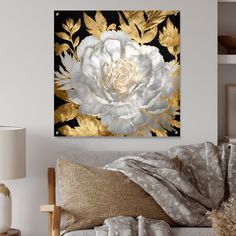 a white and gold flower on a black background in a living room with pillows, lamps and other decor