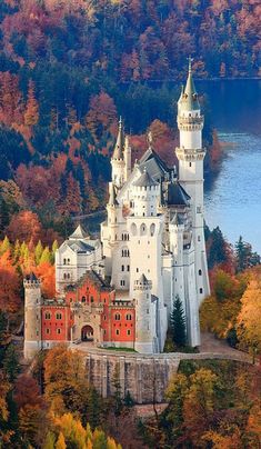 an aerial view of a castle surrounded by trees and water in the fall with colorful foliage surrounding it