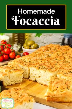 homemade focaccia bread on a cutting board with tomatoes in the background