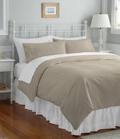 a bed with blue and white comforters in a bedroom next to a lamp on a wooden floor