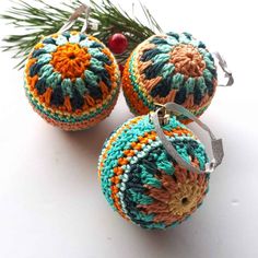 three crocheted ornaments hanging from a christmas tree branch on a white table top