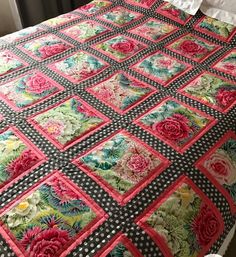 a bed with a black and white checkered bedspread covered in pink flowers