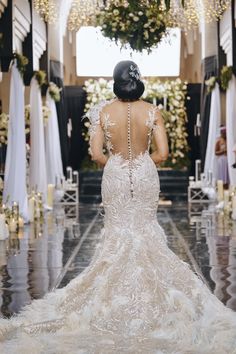 the back of a woman's wedding dress as she stands in front of an altar