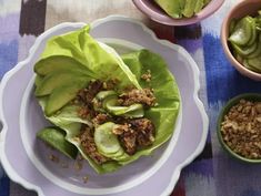 lettuce wraps with meat and vegetables on a plate next to two small bowls