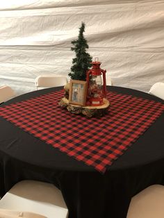 a small christmas tree is placed on top of a black tablecloth with red and white plaid