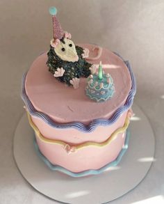 a pink cake with a hedge on top and a blue cupcake in the middle