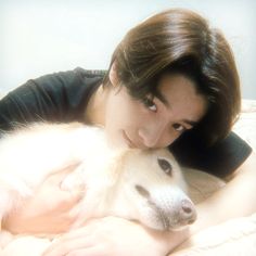 a woman laying on top of a bed next to a white dog