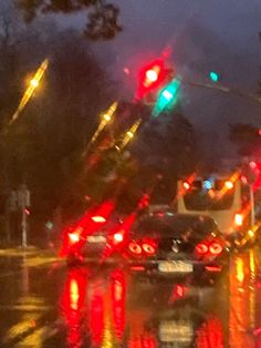 cars stopped at a red light on a rainy night in the rain with traffic lights reflecting off the wet road