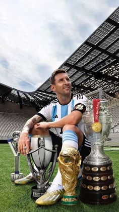 a man sitting on top of a soccer ball next to a trophy