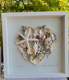 a heart made out of seashells in a white frame