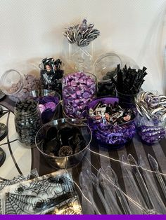 a table topped with lots of purple and black candies next to silverware dishes