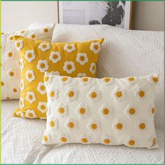 three yellow and white pillows sitting on top of a bed next to a framed photograph