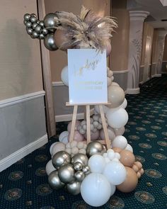 a birthday party decoration with balloons and a sign on the easel in front of it