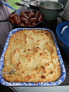 a casserole dish with meat and cheese on the table next to other dishes