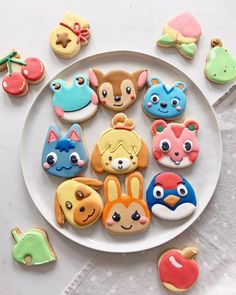 some cookies are on a plate with other decorated cookies in the shape of animals and birds