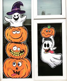 a window decorated with halloween pumpkins, ghost and jack - o'- lantern faces