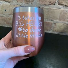 a person holding up a wine glass that says it takes a big heart to shape little minds