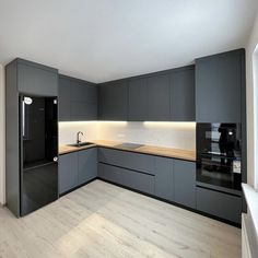 an empty kitchen with grey cabinets and black appliances