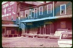 an old building with wooden benches in front of it and a car parked next to it