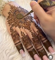 a woman is getting hendi on her hand and holding a pen in her other hand