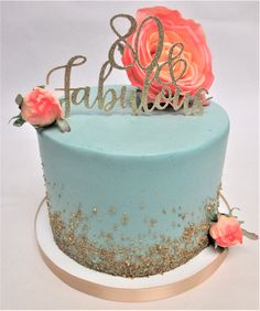 a blue cake with gold sprinkles and pink flowers on top that says fabulous