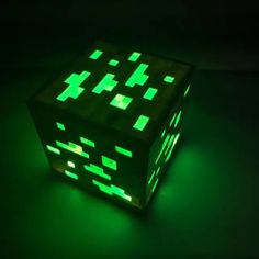 a glowing cube in the dark with green lights on it's sides and squares