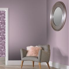 a chair in front of a purple wall with a mirror on the wall next to it