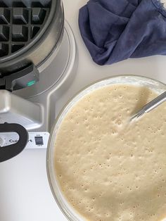 a bowl of batter next to an electric waffle maker