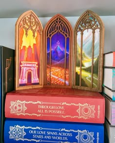 three books stacked on top of each other in front of a wall with stained glass windows