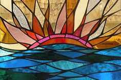 a stained glass window with the sun in it's center and blue water below