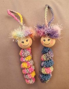 two crocheted dolls hanging from strings on a bed with the same color yarn