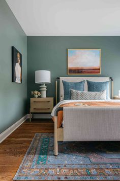 a bedroom painted in blue and green with a bed, nightstands, and painting on the wall