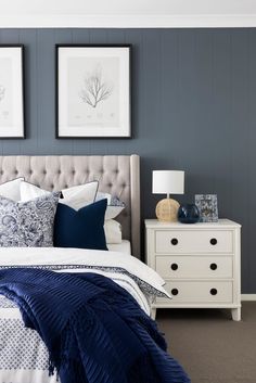 a bedroom with blue and white bedding, two pictures on the wall above it