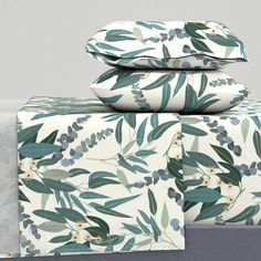 three sheets with green leaves and white flowers are stacked on top of each other in front of a gray wall