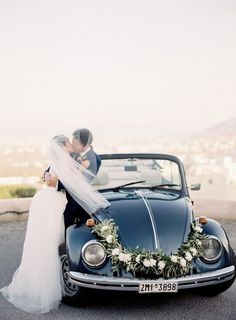 a bride and groom kissing in front of a vintage car