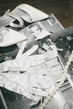 an assortment of women's shoes and jewelry on a wooden table next to magazines